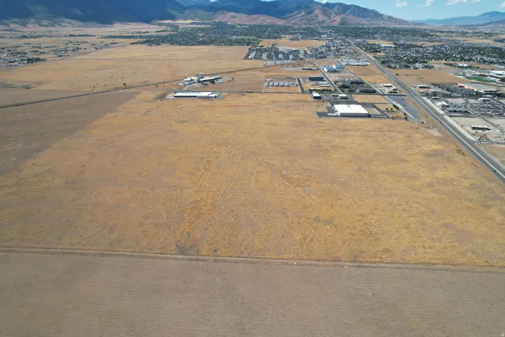 Expansive open land featuring diverse terrain, bordered by a roadway, with distant mountainous scenery