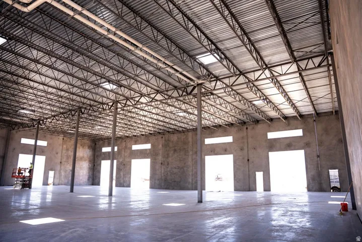 Expansive open interior with a polished concrete floor, exposed metal truss ceiling, and multiple skylights