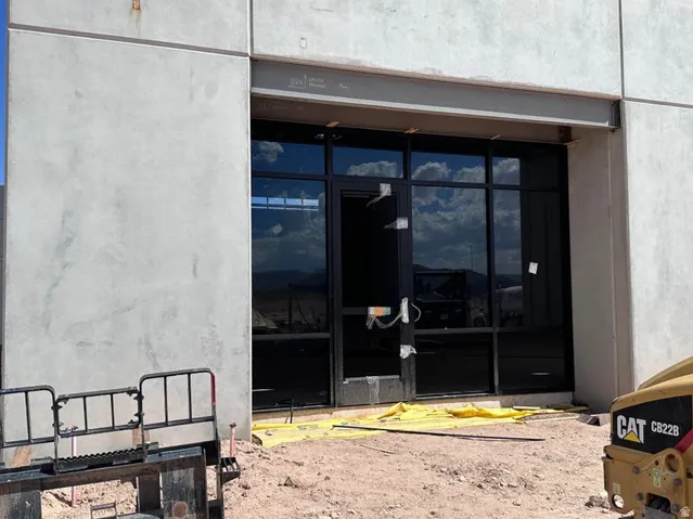 Full-height storefront glazing with black framing and a concrete panel exterior