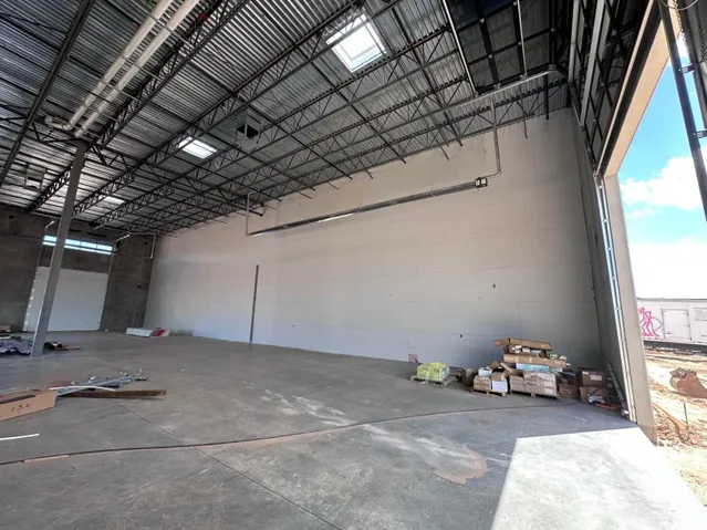 Expansive concrete flooring with a metal truss ceiling and skylights