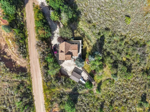 Property featuring a multi-level structure with a natural tone roof, a secondary structure, and a dirt driveway