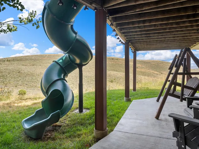 Expansive outdoor space featuring a concrete patio, wood-toned support beams, and a green spiral slide