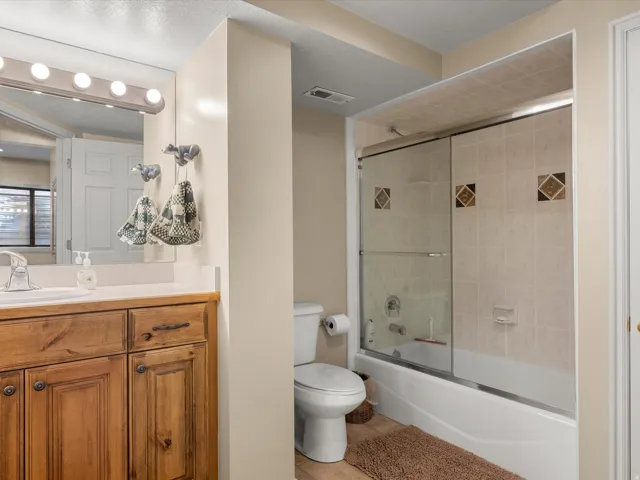 Wood vanity with dark hardware, white countertop, and integrated sink