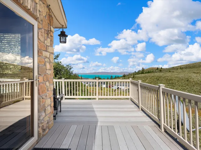 Spacious outdoor deck with composite flooring and a white railing, featuring stone exterior siding and a clear glass door