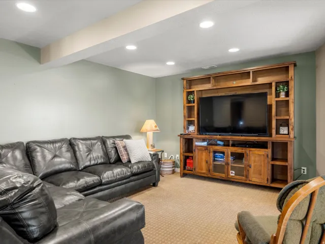 Entertainment area featuring recessed lighting, a built-in wood-finish media center, and light-colored carpeting