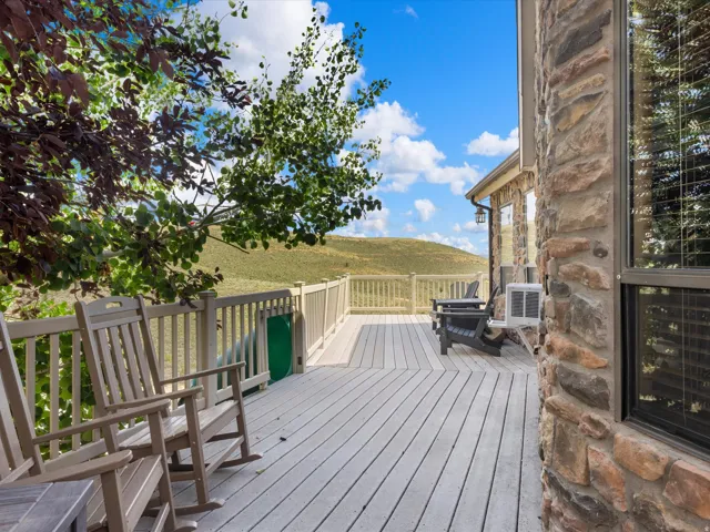 Expansive composite deck with a sturdy railing, stone exterior detailing, and a prominent window