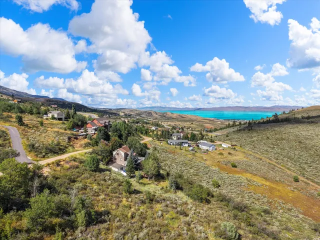 Elevated landscape with a prominent lake backdrop, featuring rolling hills and scattered residential structures