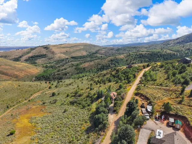 Mountainous terrain with natural vegetation, distant water body, and a winding unpaved road