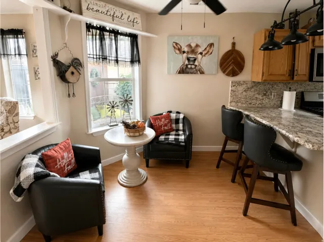 Wood-finish flooring, light-colored walls, and windows with black valances