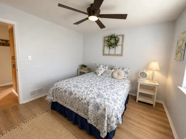 Wood-finish flooring, light wall paint, and a ceiling fan with integrated lighting