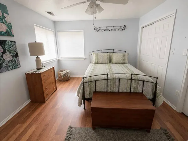 Wood-finish flooring throughout, two windows with blinds, ceiling fan, and bi-fold closet doors