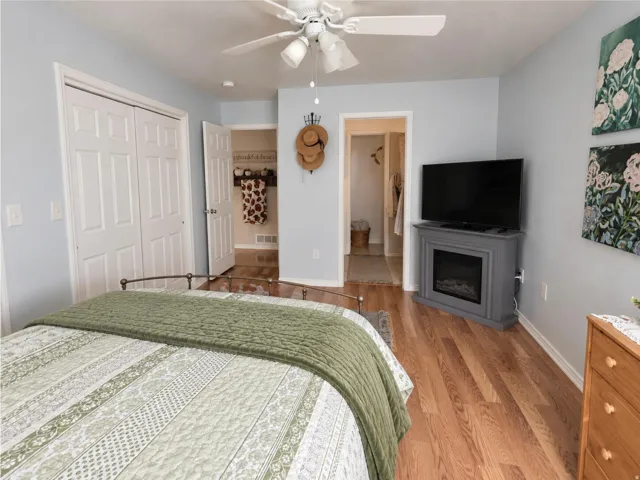 Wood-finish flooring, ceiling fan with integrated lighting, bi-fold closet doors, and light blue wall paint