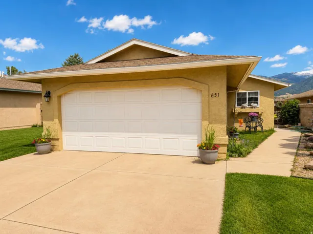 Stucco exterior with a two-car garage, concrete driveway, and established landscaping