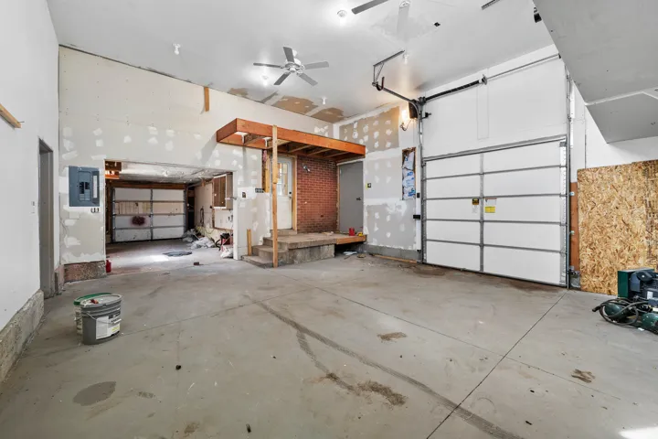 Concrete flooring with two white garage doors and exposed brick