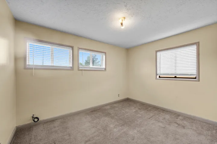 Carpeted room with multiple windows, textured ceiling, and a ceiling-mounted light fixture