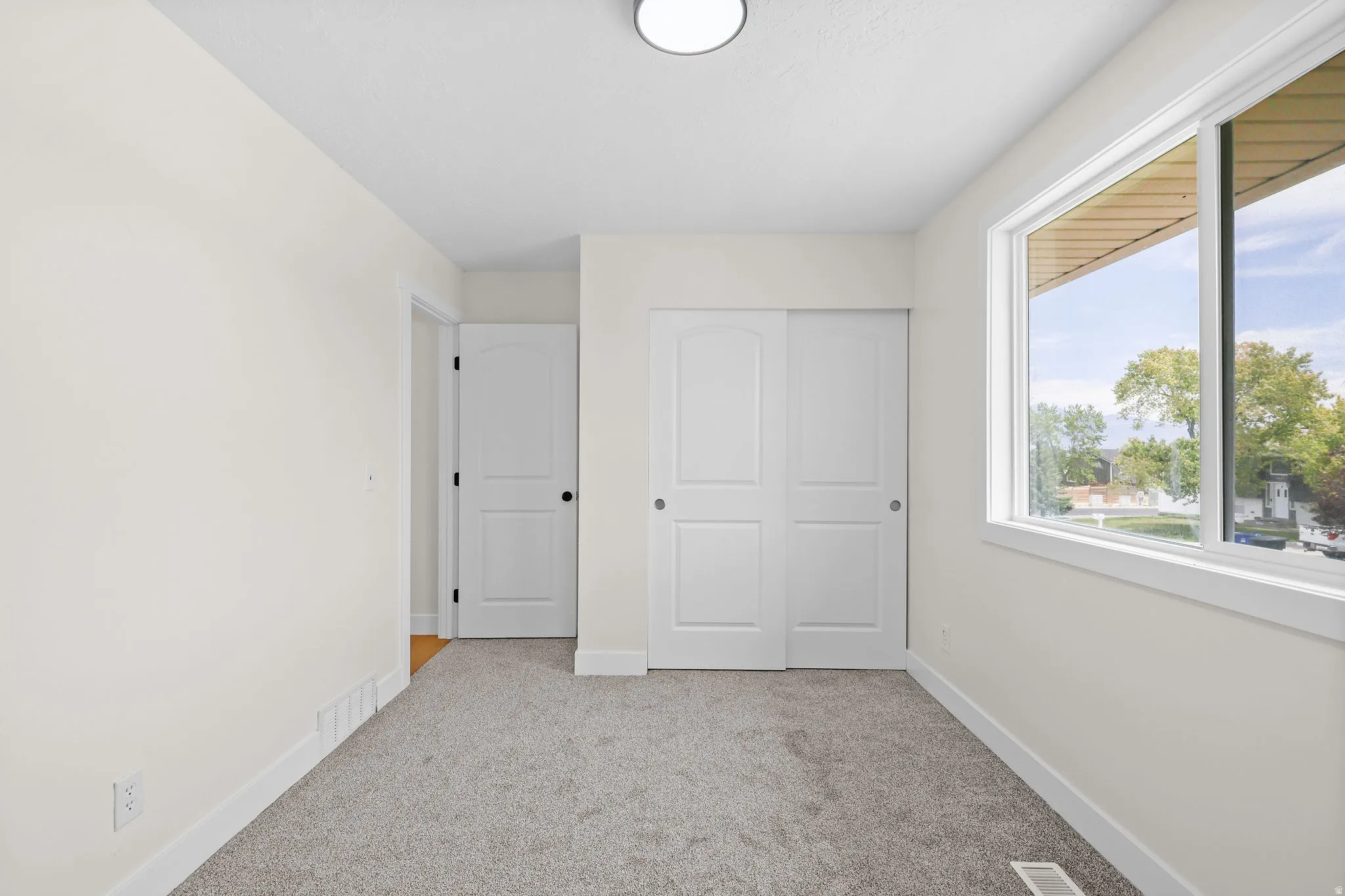 Recessed overhead lighting, carpet flooring, a large window, and sliding closet doors