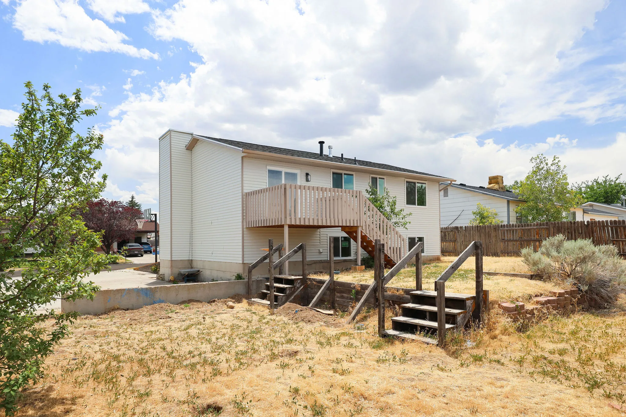 Rear exterior with white siding, multi-level wooden deck with railing, and multiple windows