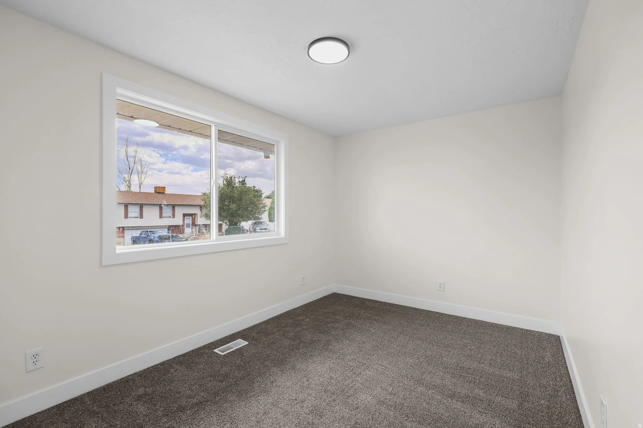 Neutral wall finishes, dark gray carpeting, and a white-framed window