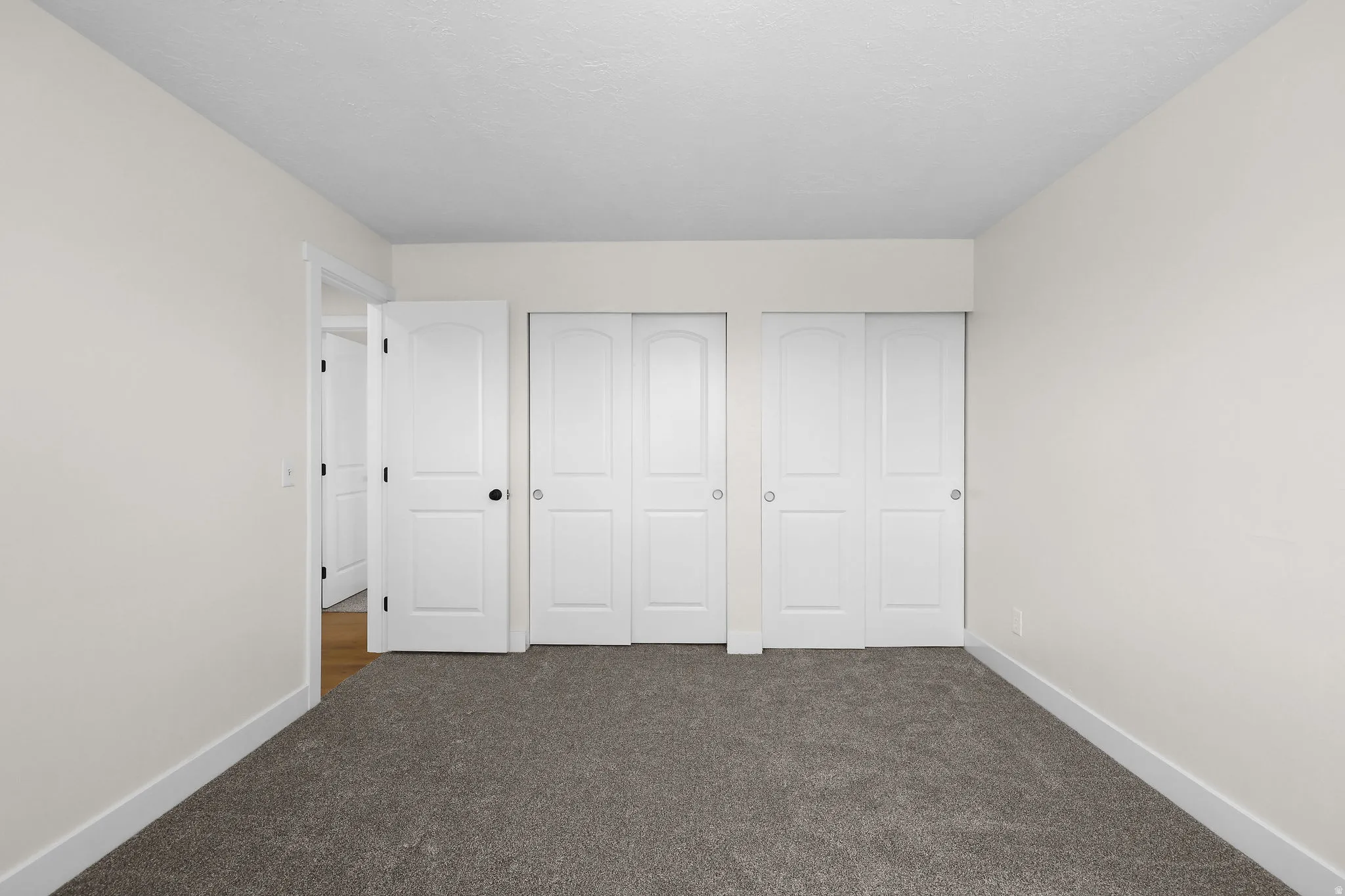 Neutral wall paint, gray carpet flooring, white trim, white interior doors, and white bi-fold closet doors