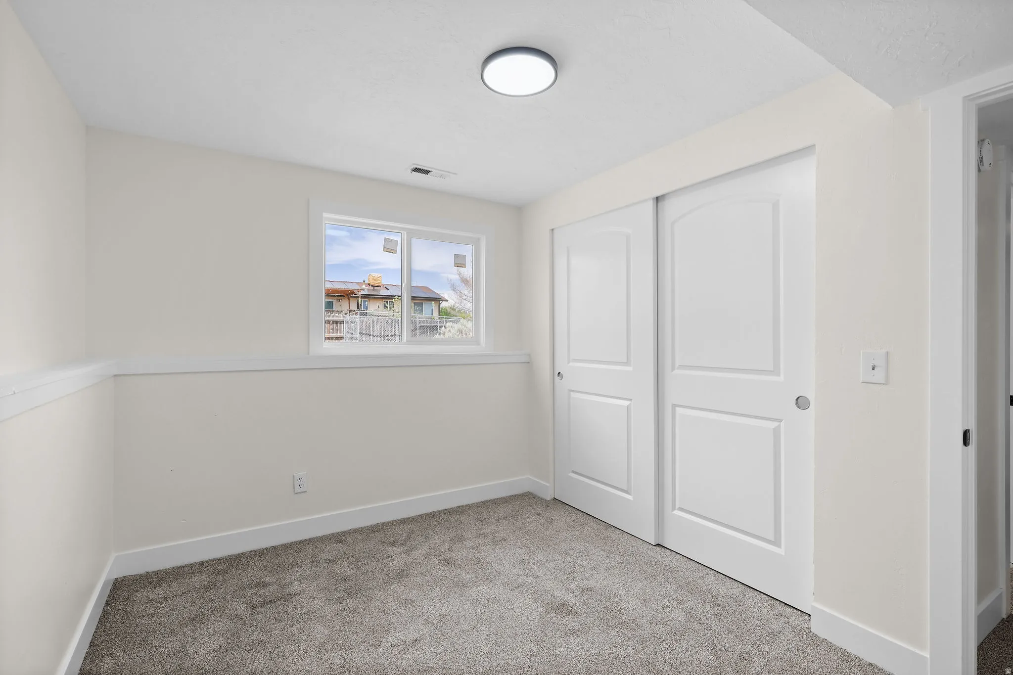 Neutral-toned carpeting, white walls, and a window with white trim