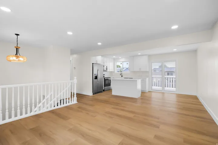 Wood-finish flooring throughout, white railing, and recessed ceiling lighting