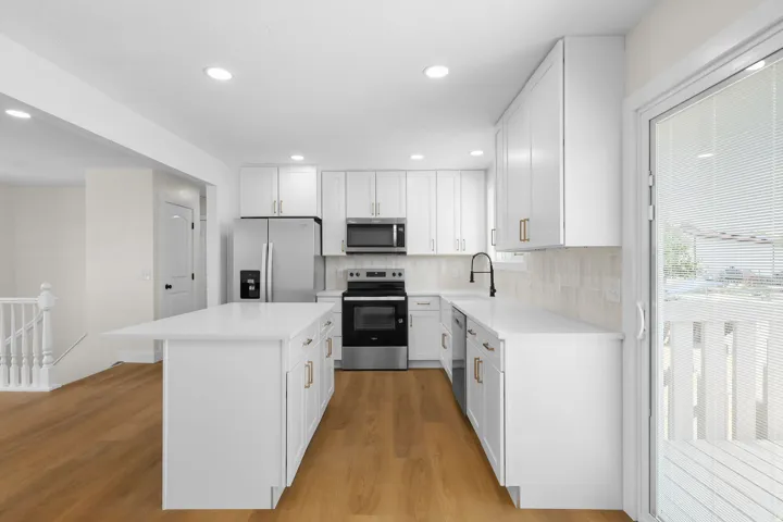 Modern kitchen featuring white cabinetry, stainless steel appliances, a center island with countertop seating, and wood-finish flooring