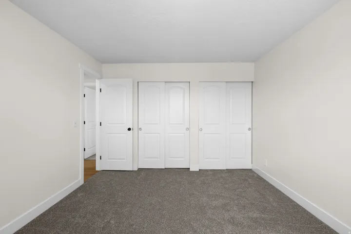 Neutral wall paint, gray carpet flooring, white trim, white interior doors, and white bi-fold closet doors