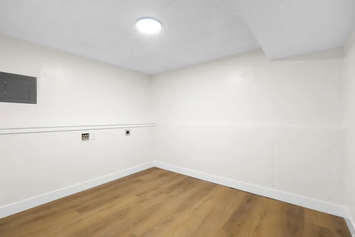 Wood-finish flooring, recessed ceiling lighting, electrical panel, and wall utility hookups