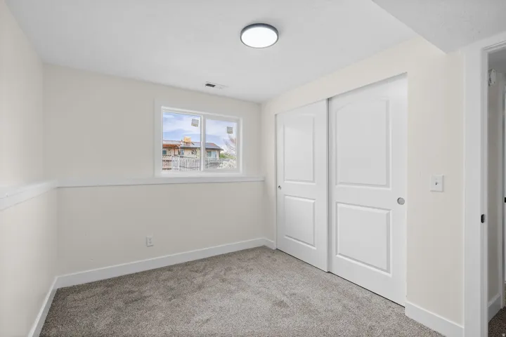 Neutral-toned carpeting, white walls, and a window with white trim