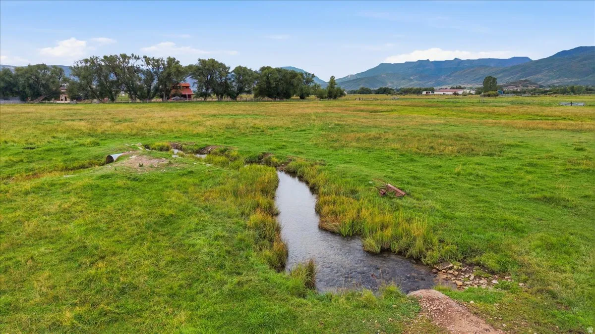 Expansive green pasture with a natural water feature