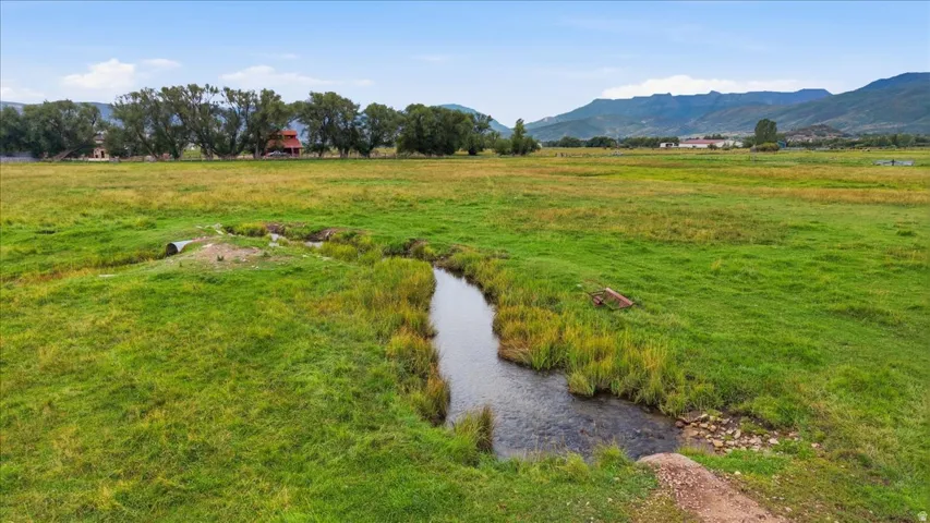Expansive green pasture with a natural water feature