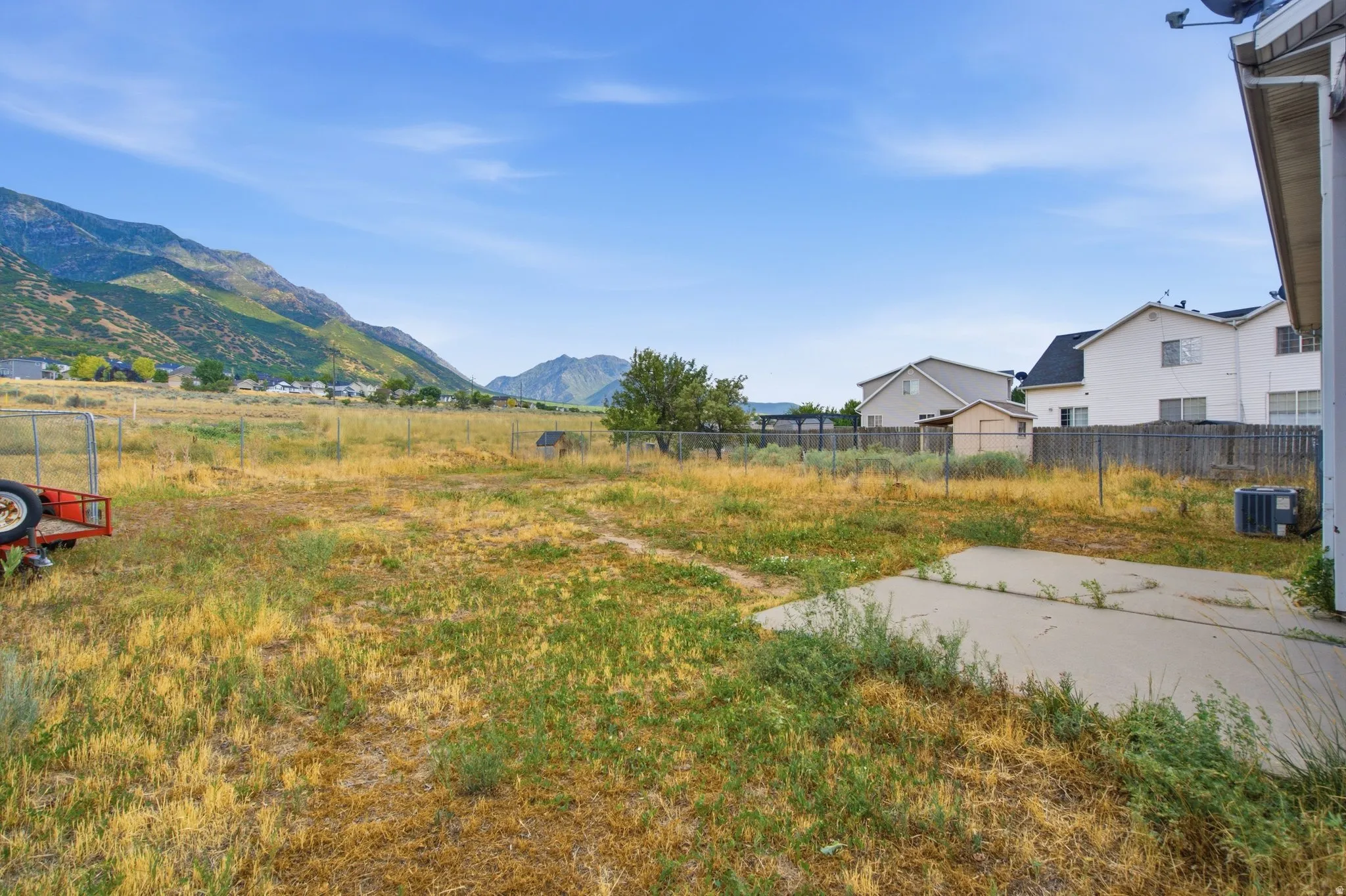 Expansive grassy area with mountain scenery and a concrete patio