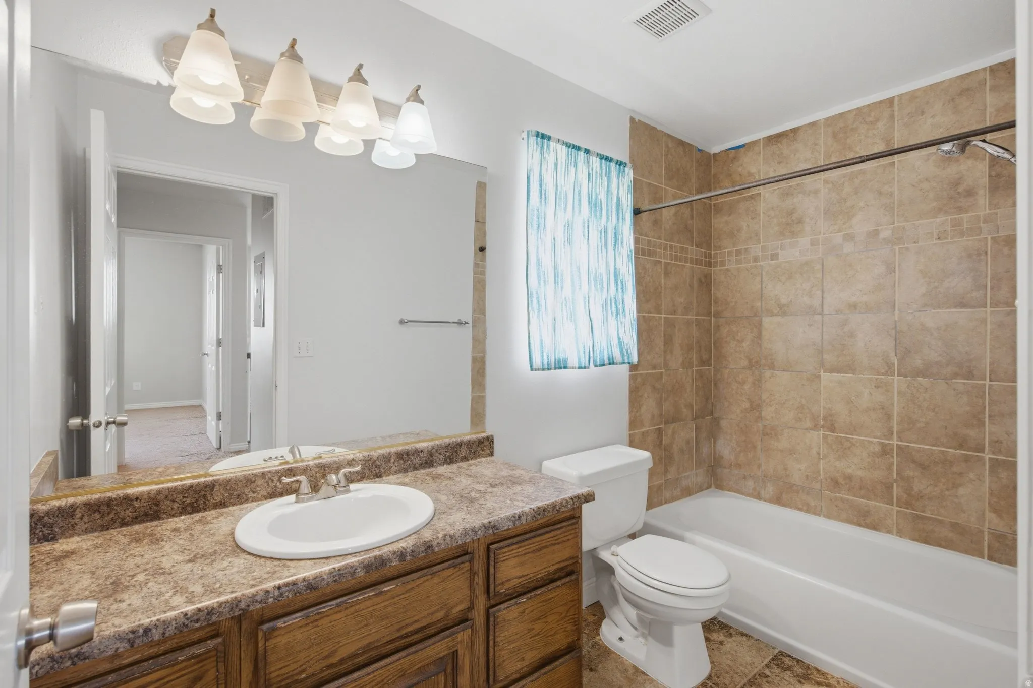 Built-in vanity with an integrated sink and wood-finish cabinetry, full-width mirror, tile-surround bathtub, and tiled flooring