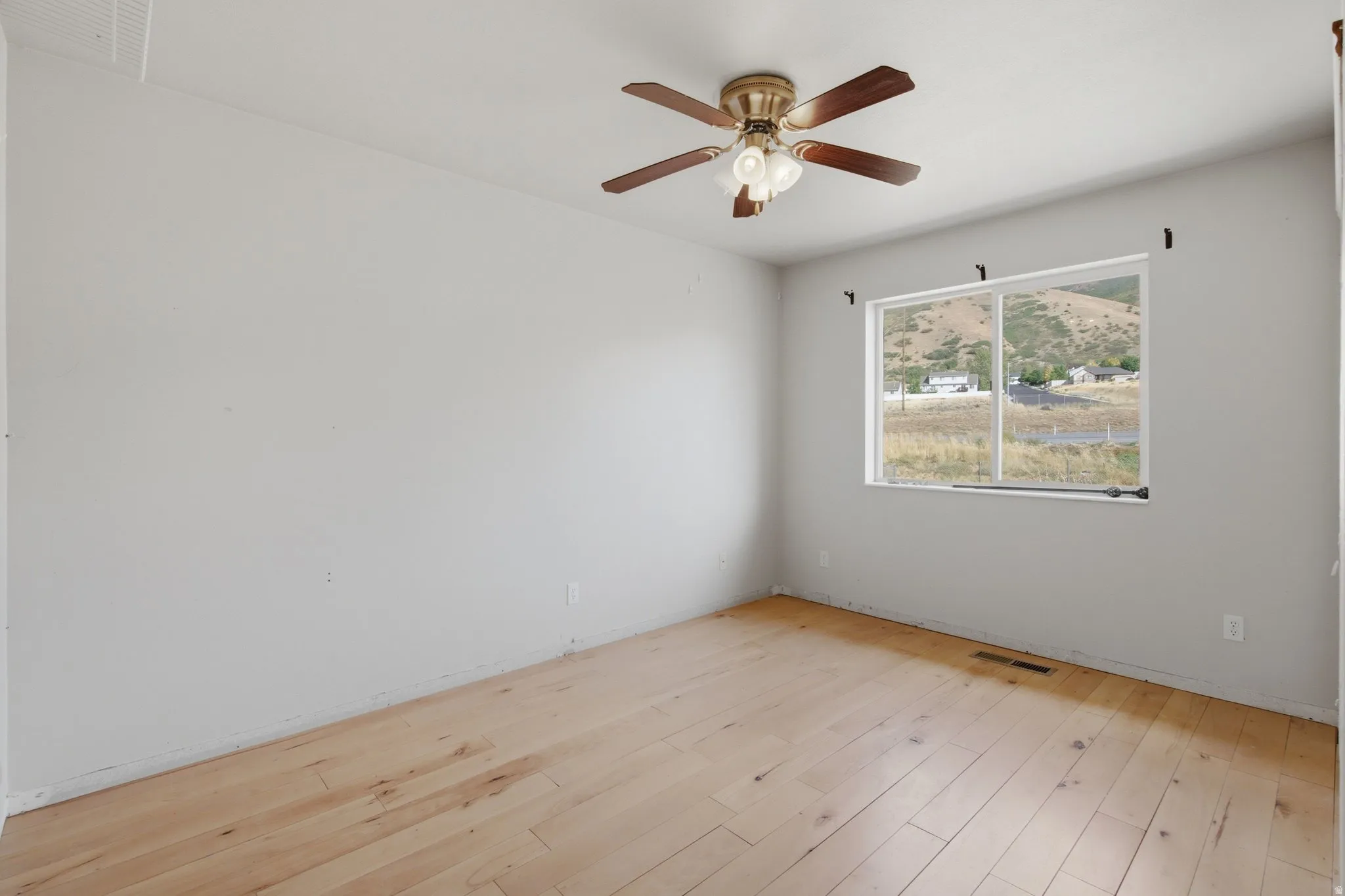 Wood-finish flooring with a ceiling fan and overhead lighting