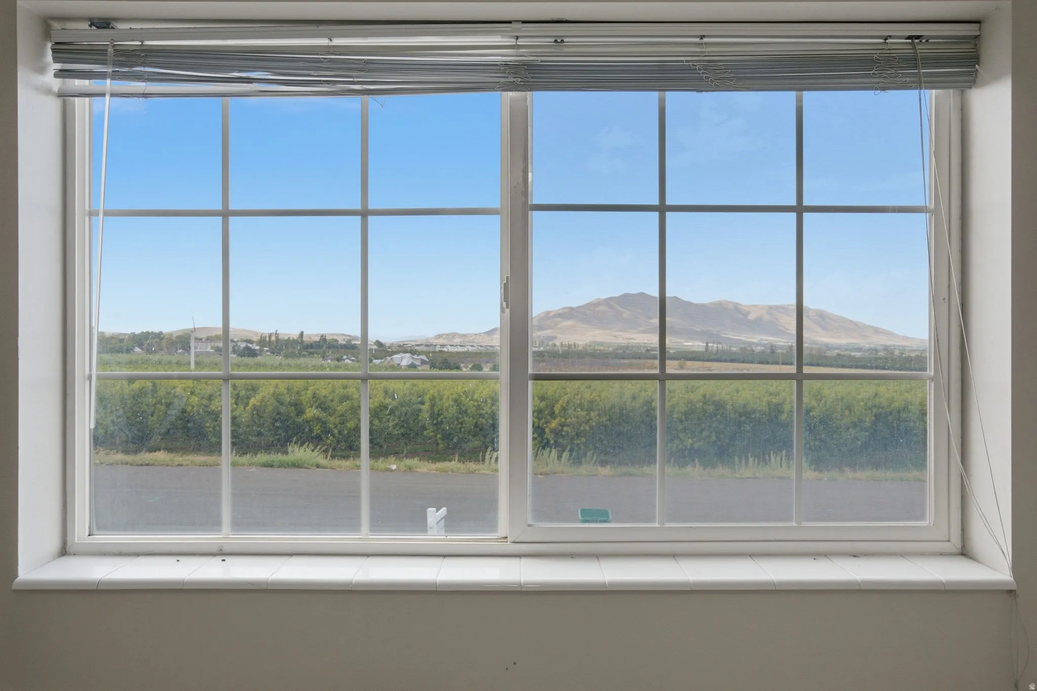 Gridded window with a tiled sill, offering expansive scenery of distant mountains and a field
