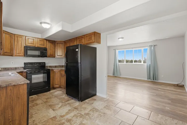 Kitchen with wood-finish cabinetry, black appliances, and tiled flooring