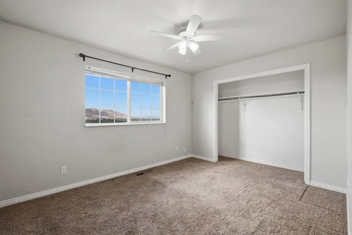 Light-filled room featuring a broad window, mountain scenery, and a ceiling fan