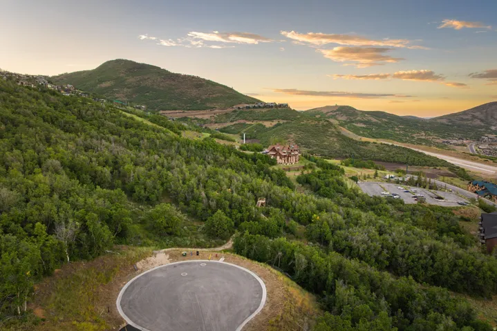 Mountainous terrain with lush green trees, paved road, and a cul-de-sac