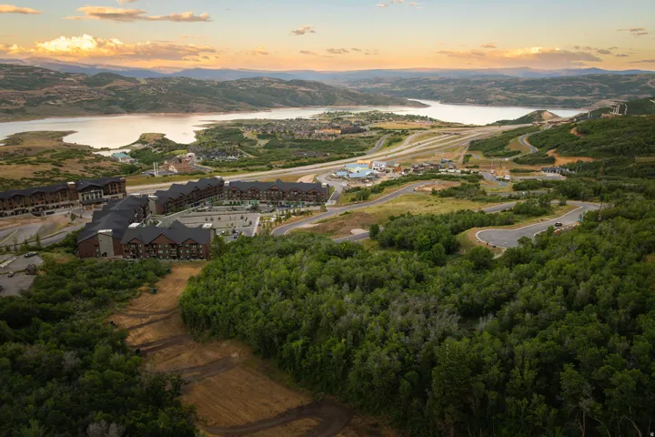 Expansive natural landscape with a prominent body of water, surrounded by rolling hills and residential structures