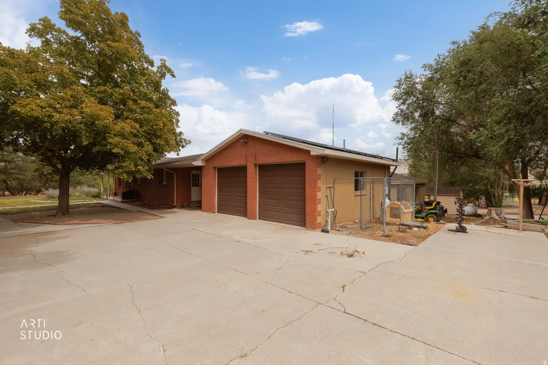 Property exterior featuring a two-car garage with individual doors, a concrete driveway, and mature trees