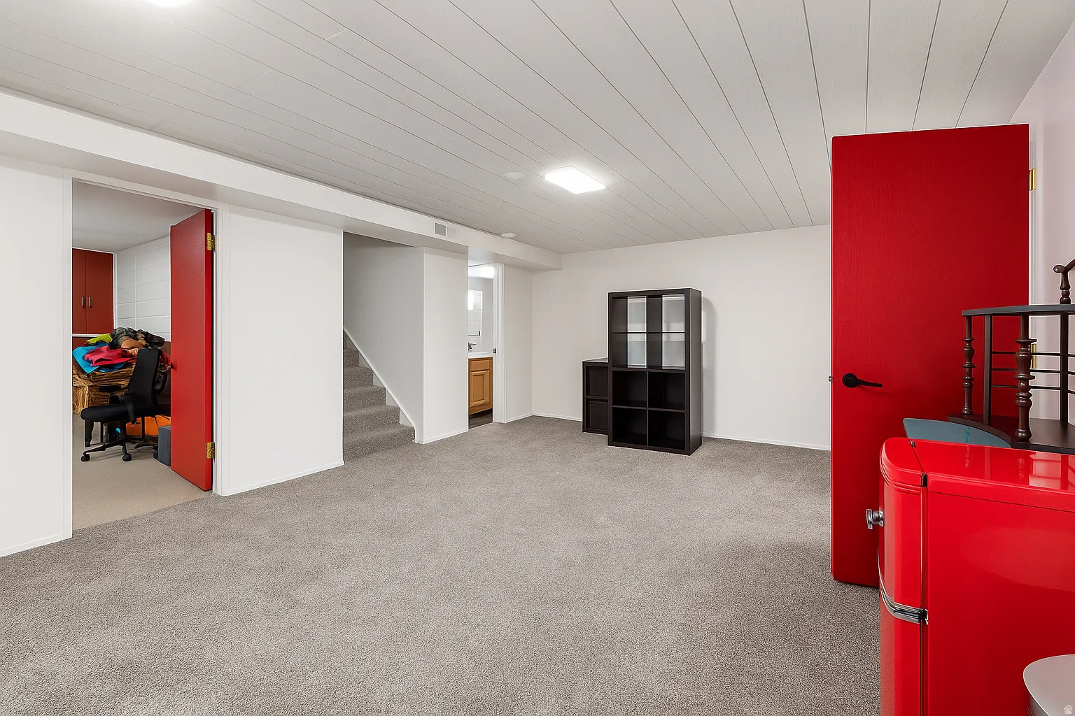 Carpeted room with white walls, white paneled ceiling, and red doors