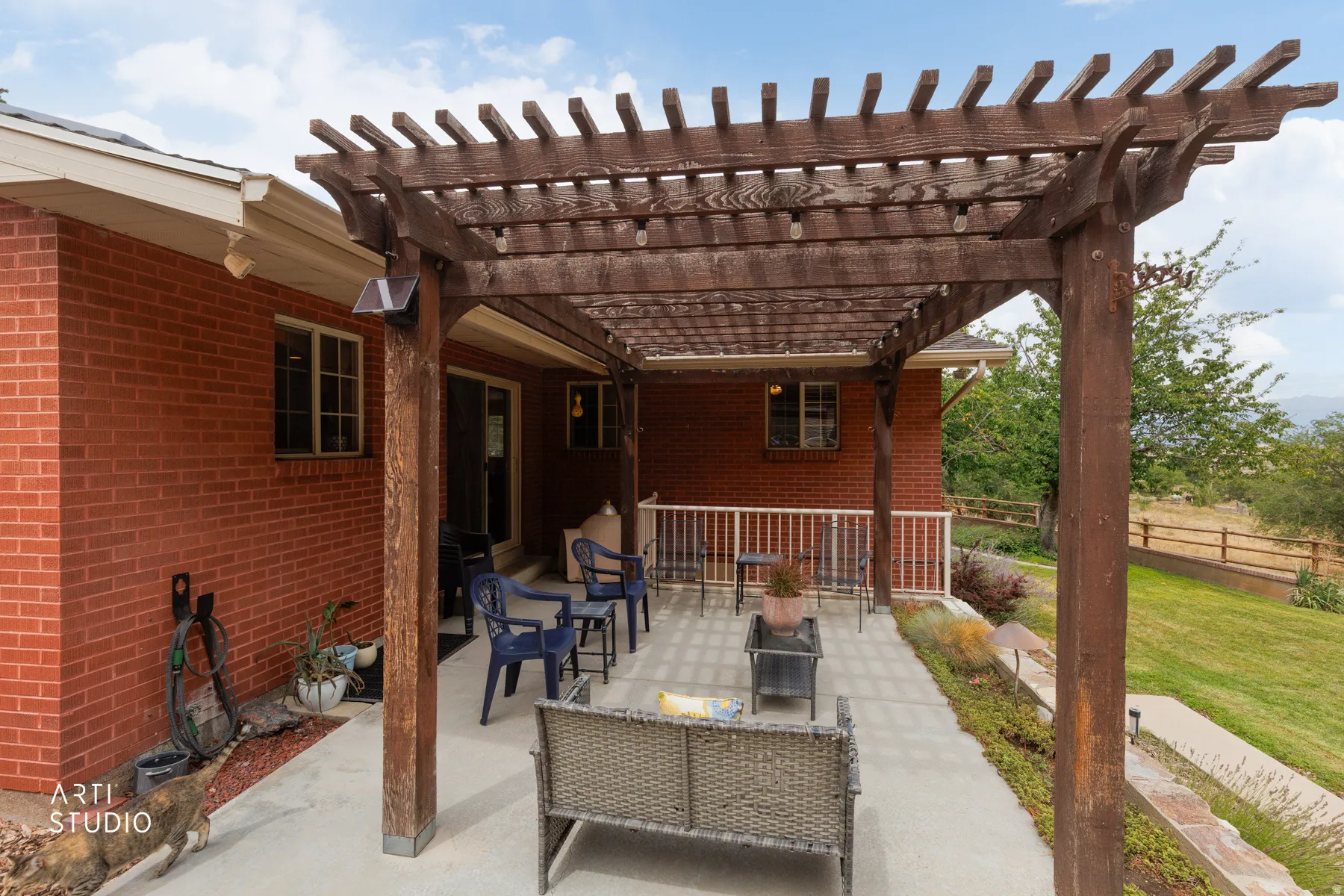 Expansive patio with a wood pergola, brick exterior, concrete hardscaping, and a sliding glass door