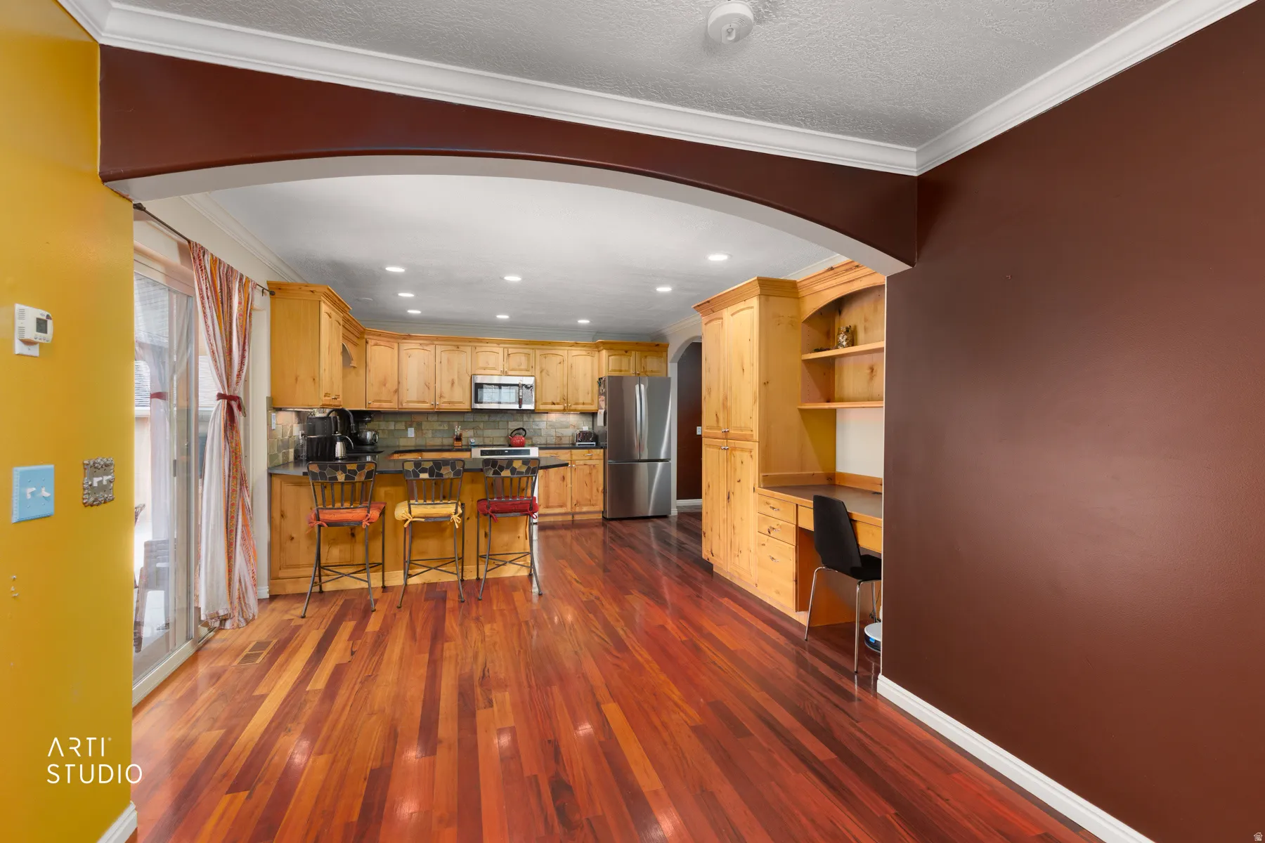 Hardwood flooring, arched doorway, recessed lighting, built-in cabinetry, and stainless steel appliances