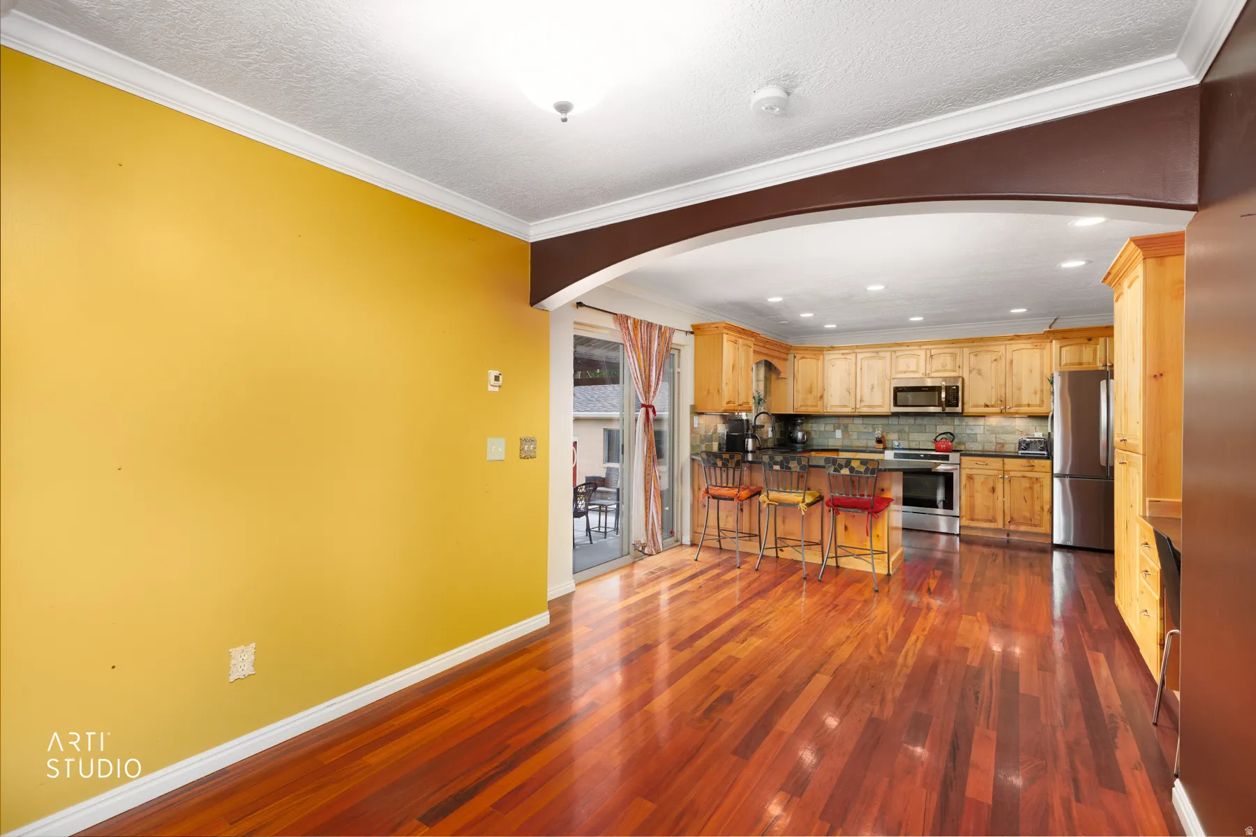 Hardwood flooring, crown molding, arched entryway, and recessed lighting