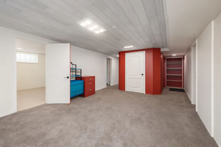 Grey carpet flooring, white plank ceiling, recessed lighting, white walls, and built-in shelving
