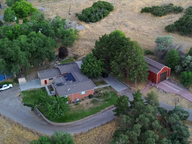 Expansive property featuring a multi-level residence, detached red barn-style outbuilding, paved driveway, and mature landscaping