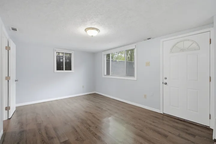 Wood-finish flooring, white trim, and two pane windows with blinds