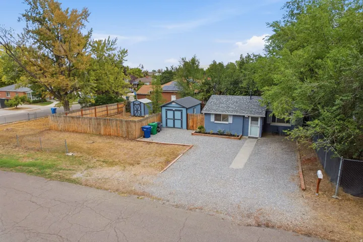 Exterior featuring a blue facade, a grey shingle roof, and a gravel driveway
