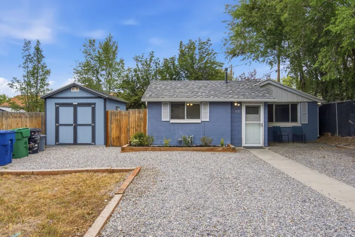 Gravel driveway and front yard with wood-framed garden bed