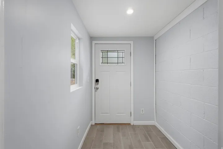 Entryway featuring a white door with frosted glass detailing, wood-finish flooring, a window, recessed lighting, and painted cinder block wall